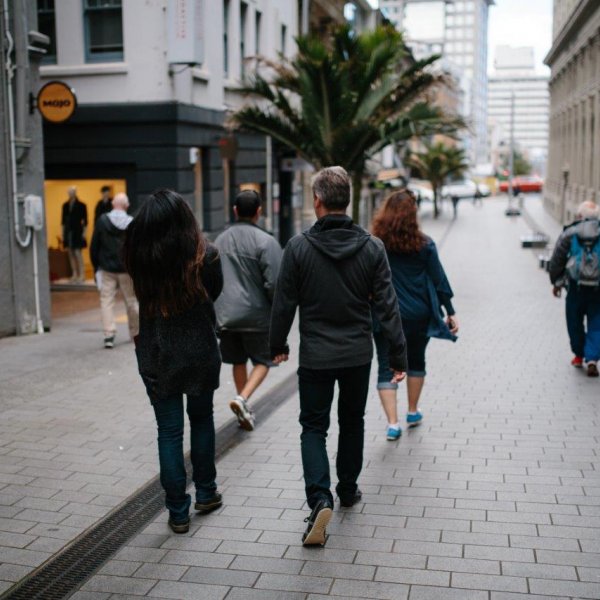 People walking in the O'Connell Street shared space in Auckland's city centre, with a Nikau palm and Mojo coffee sign in the background. Image: Sacha Stejko.