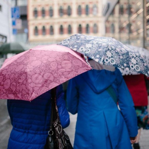 Pedestrians walking up Fort Lane towards Customs Street in the rain with umberellas and view of the Old Sofrana Building