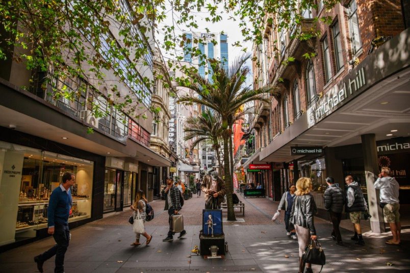Vulcan Lane view of trees, shoppers, pedestrians, shops and architecture of the surrounding buildings