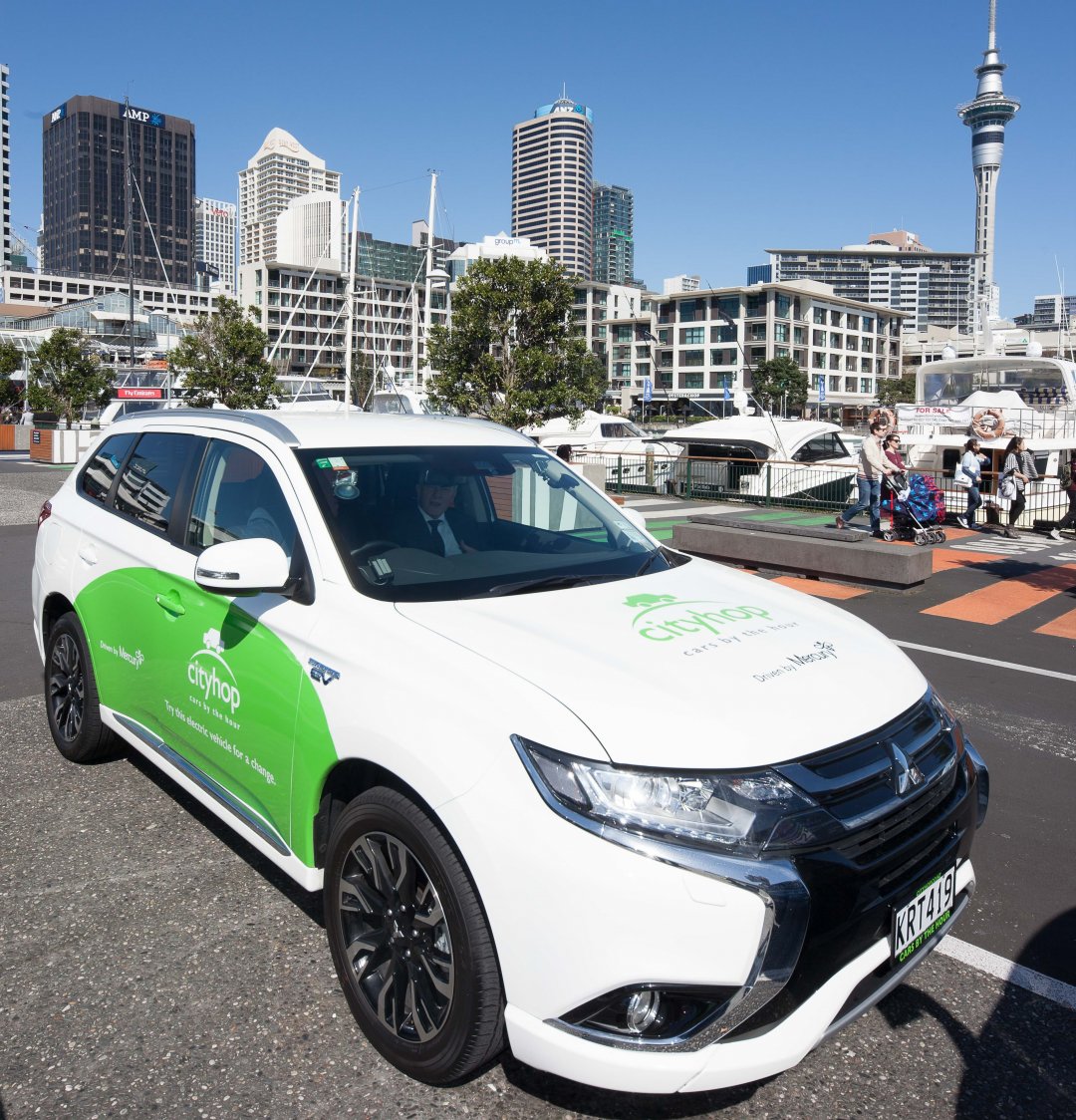 Cityhop car share on Auckland City Centres viaduct with view of skytower, tower blocks, water, boats, pedestrians, and restaurants